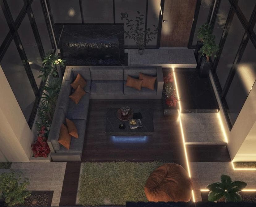 Sunken outdoor majlis seen from above at night: floor cushions, a low table and LED strips set into the deck and planters