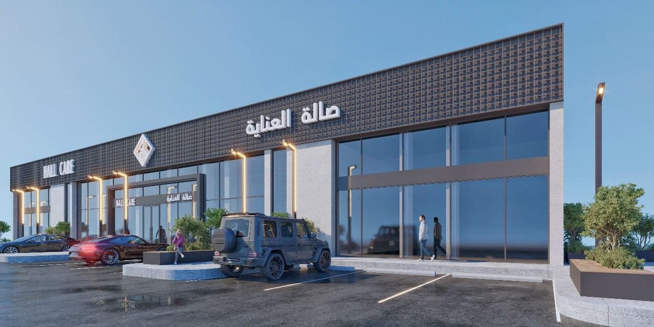 Two-storey retail strip clad in perforated bronze mesh with a backlit signage band, seen from the car park at dusk